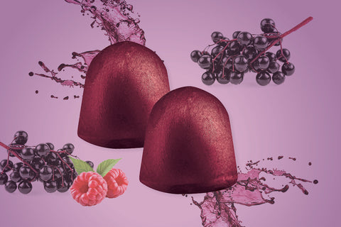 2 elderberry gummies with fruits and splashes of juice behind them 