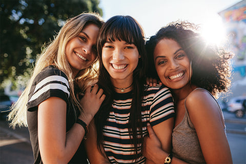 three friends smiling together in the sunshine 