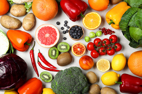 countertop with fruits and vegetables, including broccoli, peppers, lemons, potatoes and strawberries